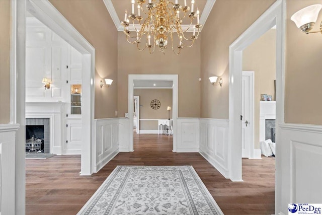 corridor with wood-type flooring, a chandelier, and crown molding