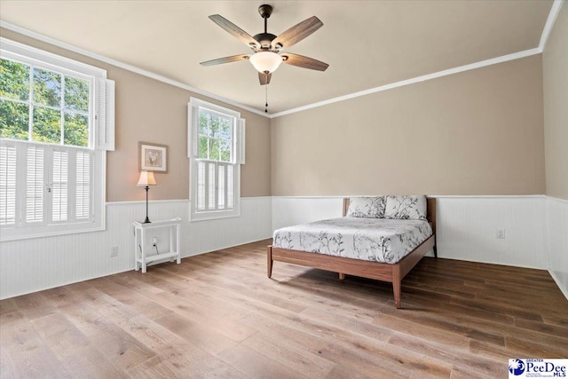 bedroom featuring wood-type flooring, ornamental molding, and ceiling fan