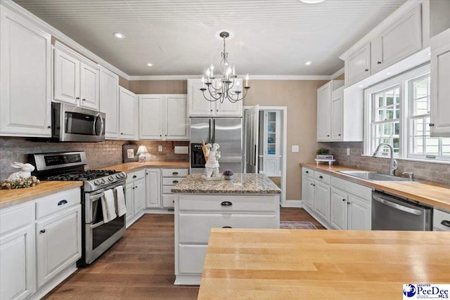 kitchen featuring sink, appliances with stainless steel finishes, hanging light fixtures, a center island, and white cabinets