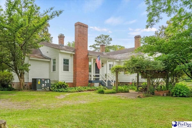 rear view of house with cooling unit and a lawn