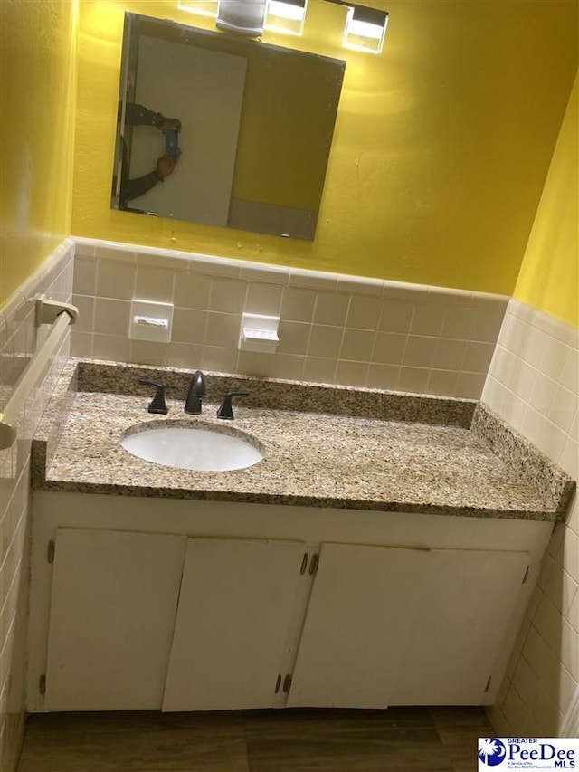 bathroom featuring hardwood / wood-style flooring, vanity, and tile walls