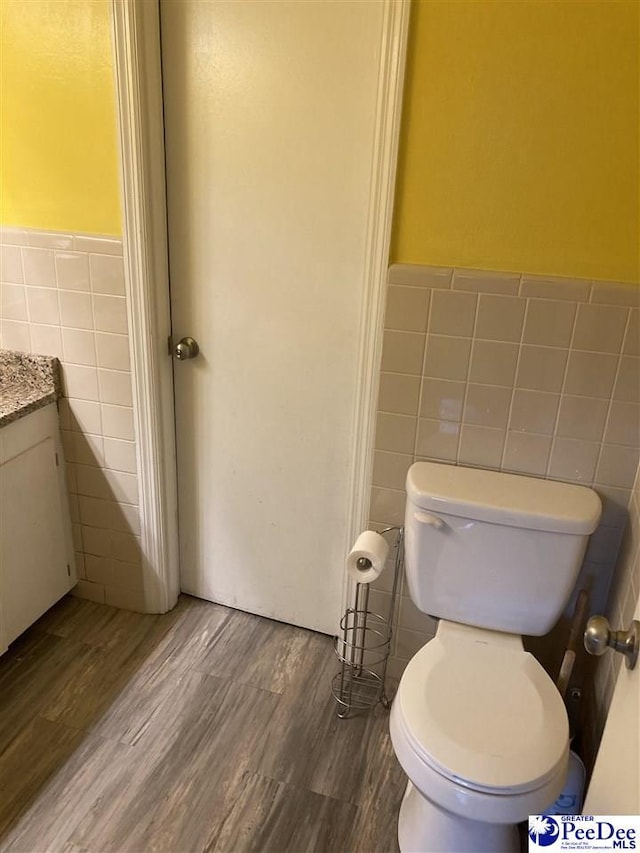 bathroom with tile walls, vanity, hardwood / wood-style flooring, and toilet