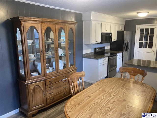 kitchen with crown molding, stainless steel appliances, dark stone counters, and white cabinets