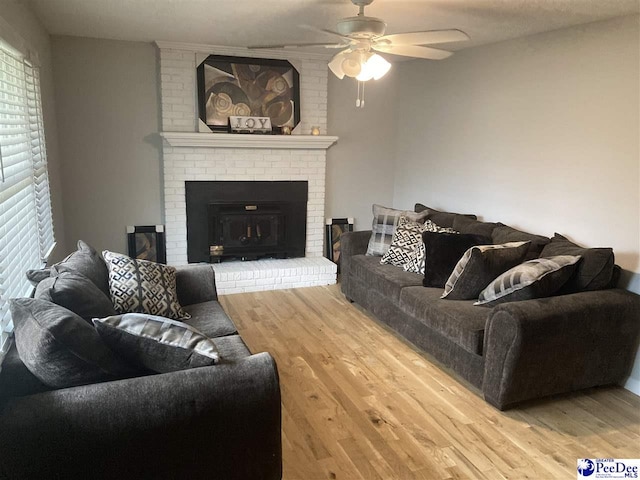 living room featuring ceiling fan, hardwood / wood-style floors, and a brick fireplace