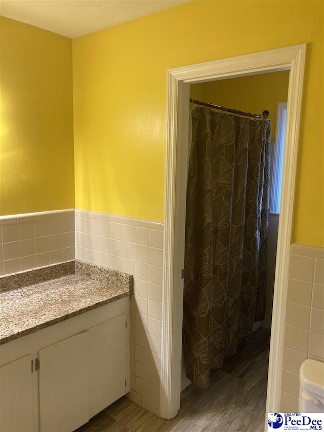 bathroom featuring tile walls, hardwood / wood-style floors, and vanity