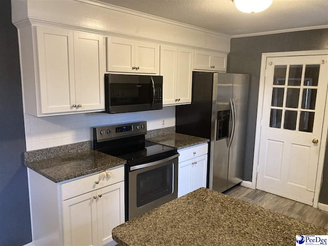 kitchen with appliances with stainless steel finishes, white cabinets, and dark stone counters