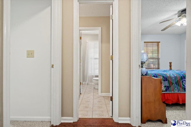 corridor with a textured ceiling and light tile patterned floors