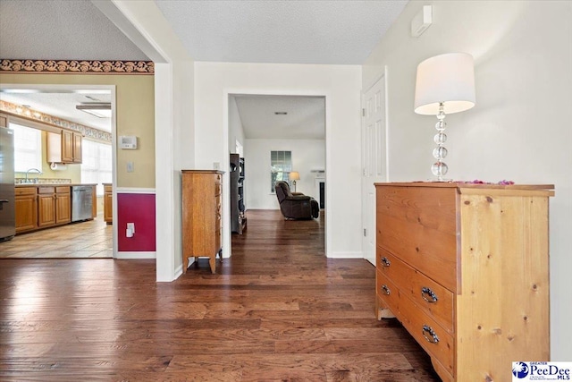 corridor with sink, dark wood-type flooring, and a textured ceiling