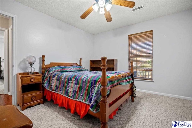 bedroom featuring ceiling fan, light carpet, and a textured ceiling