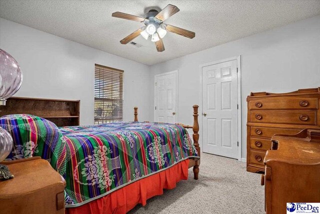 carpeted bedroom with ceiling fan and a textured ceiling