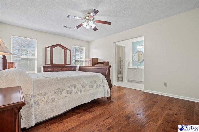 bedroom featuring hardwood / wood-style flooring, ceiling fan, ensuite bathroom, and a textured ceiling