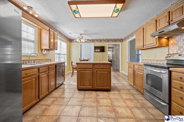 kitchen featuring sink, a center island, a textured ceiling, ceiling fan, and stainless steel appliances