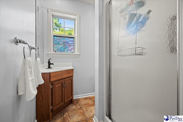 bathroom with a shower with door, vanity, and tile patterned floors