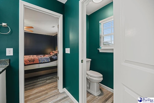 bathroom with wood-type flooring, vanity, ceiling fan, and toilet