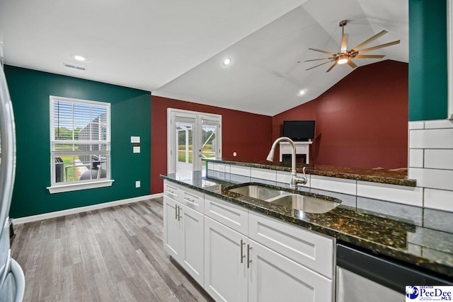 kitchen with sink, light hardwood / wood-style flooring, white cabinetry, dark stone countertops, and stainless steel dishwasher