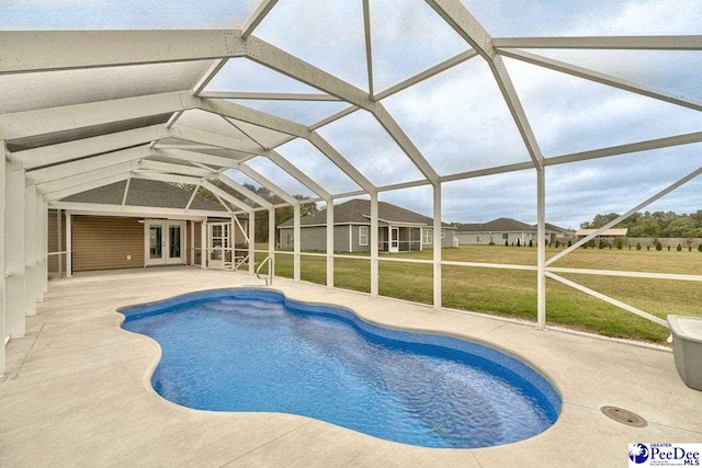 view of pool with a yard, a patio area, glass enclosure, and french doors