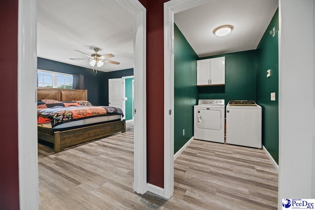 clothes washing area with cabinets, ceiling fan, washer and clothes dryer, and light hardwood / wood-style flooring