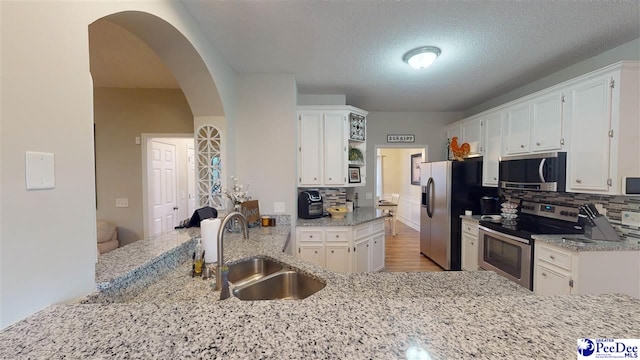 kitchen with tasteful backsplash, sink, stainless steel appliances, and white cabinets