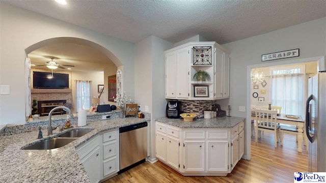 kitchen featuring sink, white cabinetry, stainless steel appliances, light hardwood / wood-style floors, and light stone countertops