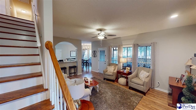 living room with ceiling fan, light hardwood / wood-style flooring, and a textured ceiling