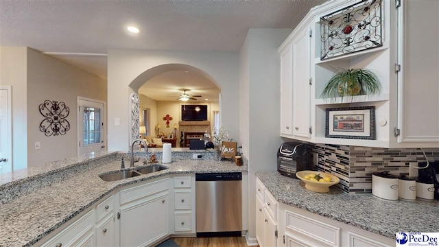 kitchen featuring dishwasher, light stone countertops, sink, and white cabinets