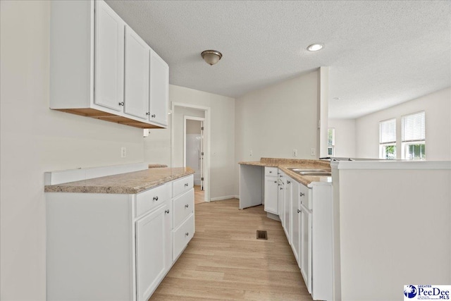 1763 Lipscomb Rd, Mullins, SC 29574 - kitchen with light wood finished floors, a textured ceiling, white cabinetry, light countertops, and a peninsula