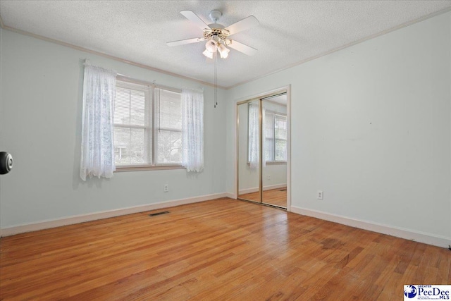 2810 Boxwood Ave, Florence, SC 29501 - unfurnished bedroom with a textured ceiling, light wood-style floors, crown molding, a closet, and a ceiling fan