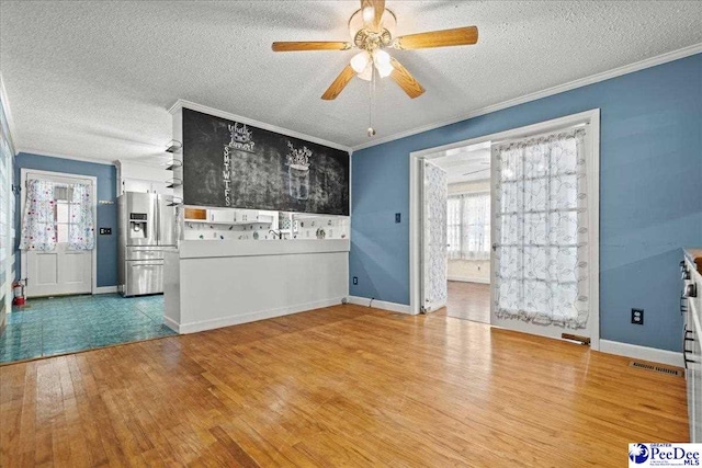2810 Boxwood Ave, Florence, SC 29501 - unfurnished living room with wood finished floors, ornamental molding, a textured ceiling, a ceiling fan, and baseboards