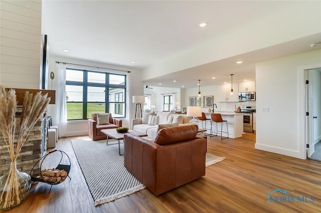 living room featuring sink, light hardwood / wood-style floors, and a stone fireplace