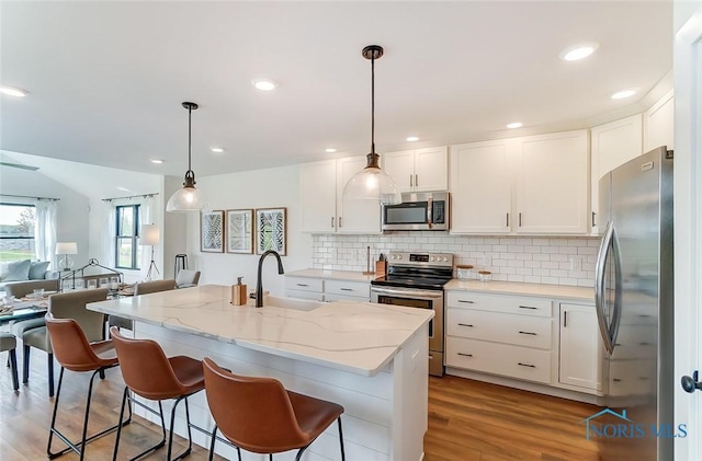 kitchen featuring white cabinetry, a breakfast bar, light hardwood / wood-style floors, sink, and stainless steel appliances