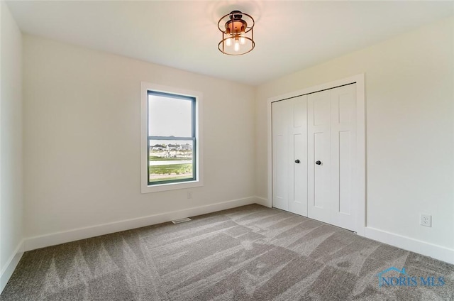 unfurnished bedroom with light colored carpet and a closet