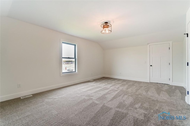 spare room with light colored carpet and vaulted ceiling