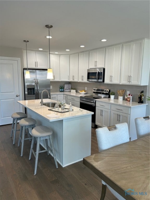 kitchen with decorative light fixtures, white cabinets, dark wood-type flooring, stainless steel appliances, and sink