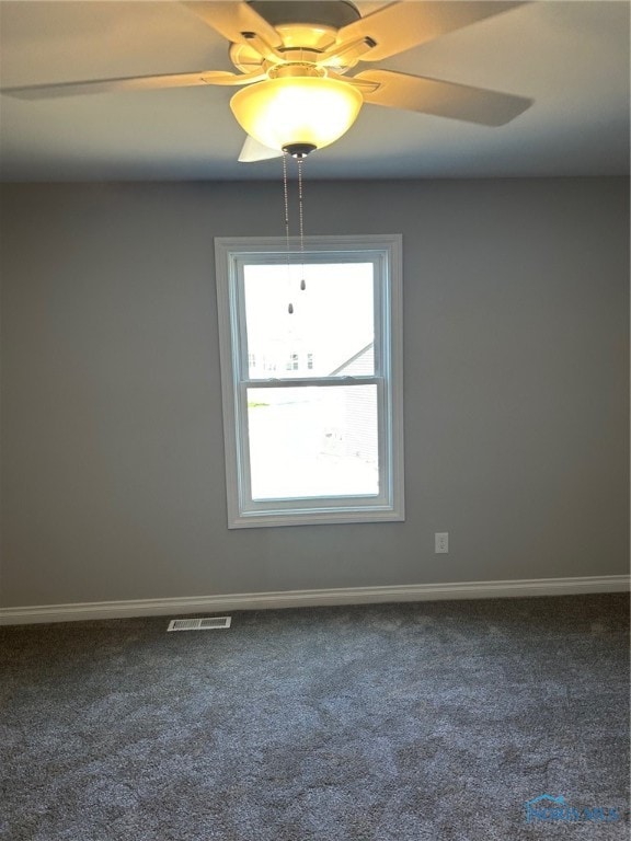 unfurnished room featuring a wealth of natural light and dark carpet