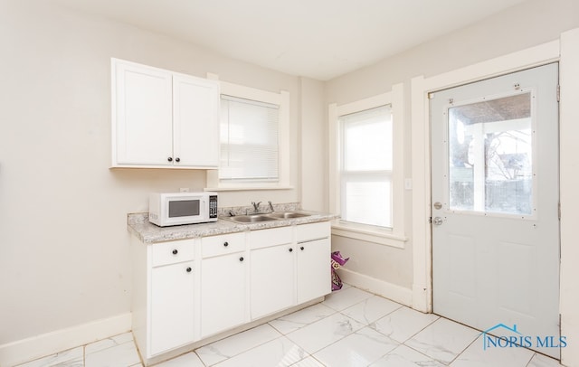 kitchen featuring light tile flooring, white cabinets, and sink