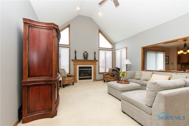 living room with high vaulted ceiling, ceiling fan with notable chandelier, and light carpet