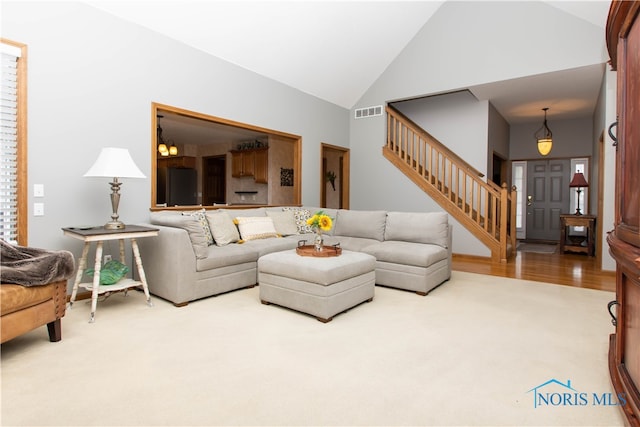 living room with light colored carpet, high vaulted ceiling, and a chandelier