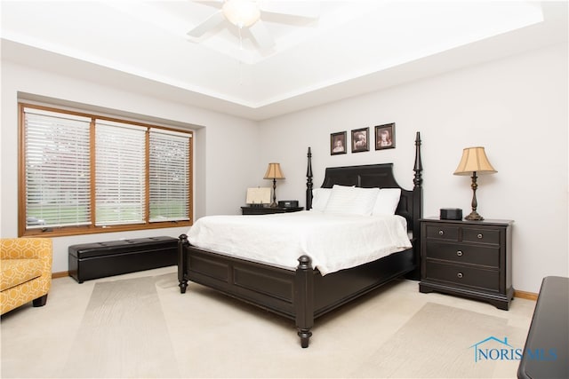 carpeted bedroom featuring a tray ceiling and ceiling fan