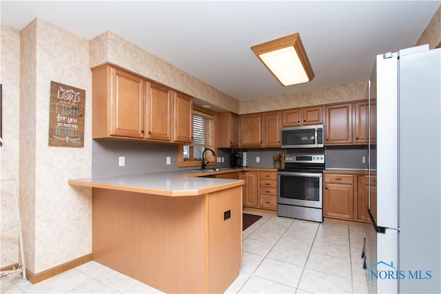 kitchen with sink, appliances with stainless steel finishes, light tile flooring, and kitchen peninsula