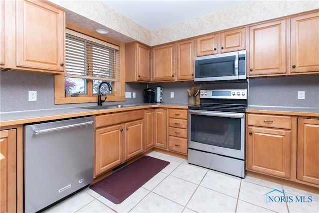 kitchen featuring appliances with stainless steel finishes, sink, and light tile floors