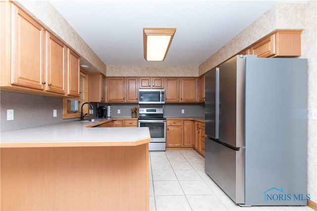 kitchen with appliances with stainless steel finishes, sink, kitchen peninsula, and light tile floors