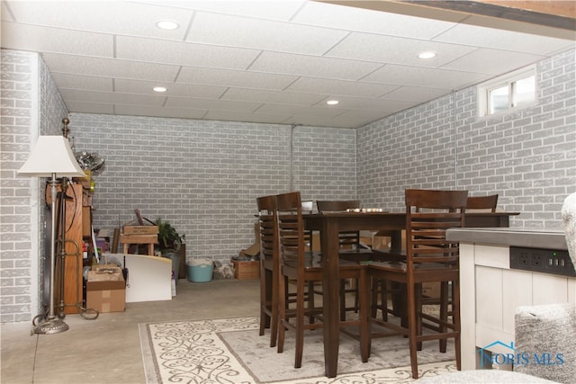 dining space with brick wall and a paneled ceiling