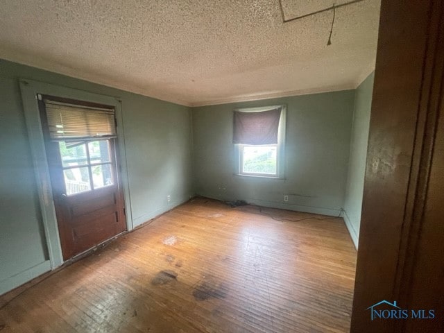 unfurnished room with a textured ceiling and wood-type flooring