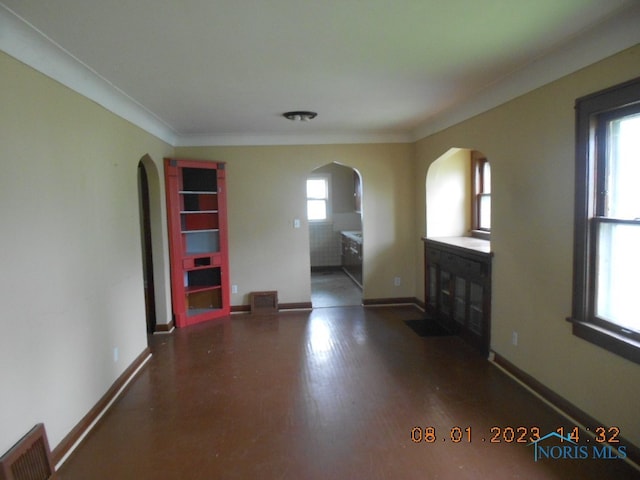 unfurnished living room with dark hardwood / wood-style flooring, a healthy amount of sunlight, and ornamental molding