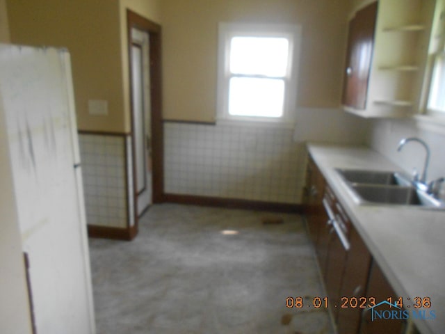 kitchen with tile walls, white refrigerator, and sink