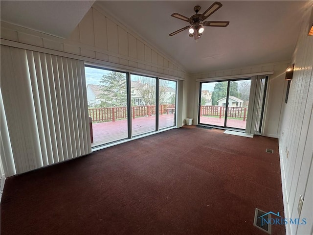 empty room featuring a wealth of natural light, carpet, and lofted ceiling