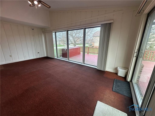 spare room with ceiling fan, dark carpet, and lofted ceiling