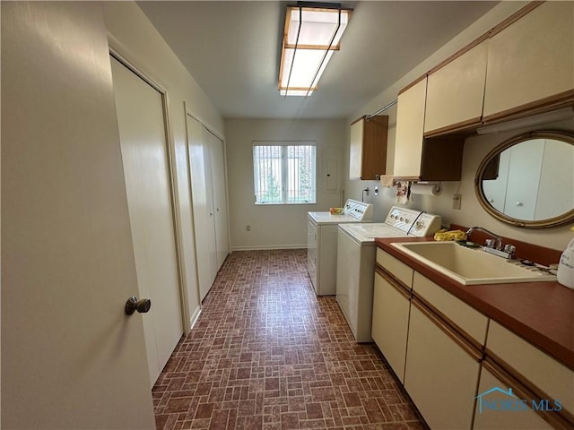 washroom with cabinets, independent washer and dryer, and sink