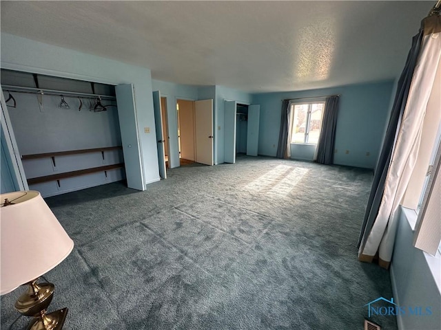 unfurnished bedroom featuring dark carpet and a textured ceiling