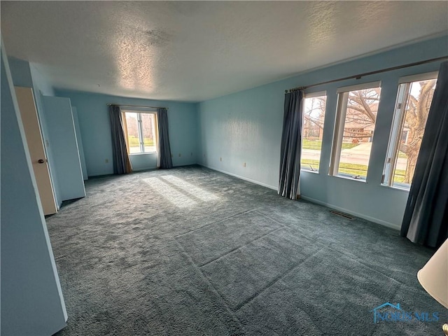 carpeted empty room with a textured ceiling